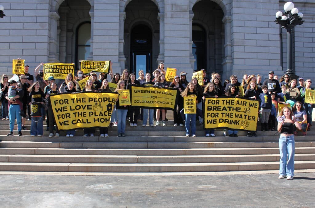 A group of about three dozen high school students stand on the steps of the Colorado Capital holding signs and banners that say Green New Deal for Schools and Our Schools Our Futures.