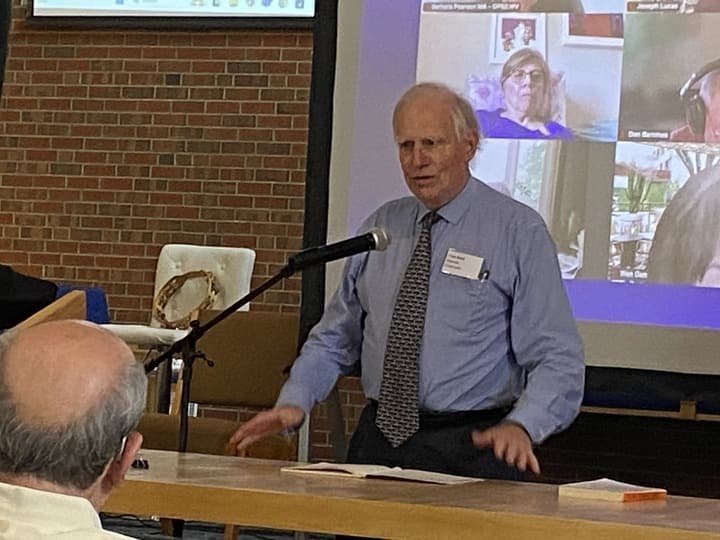 A man dressed in blue shirt and tie gestures as he addresses a room of people interested in reforming America's health insurance system.