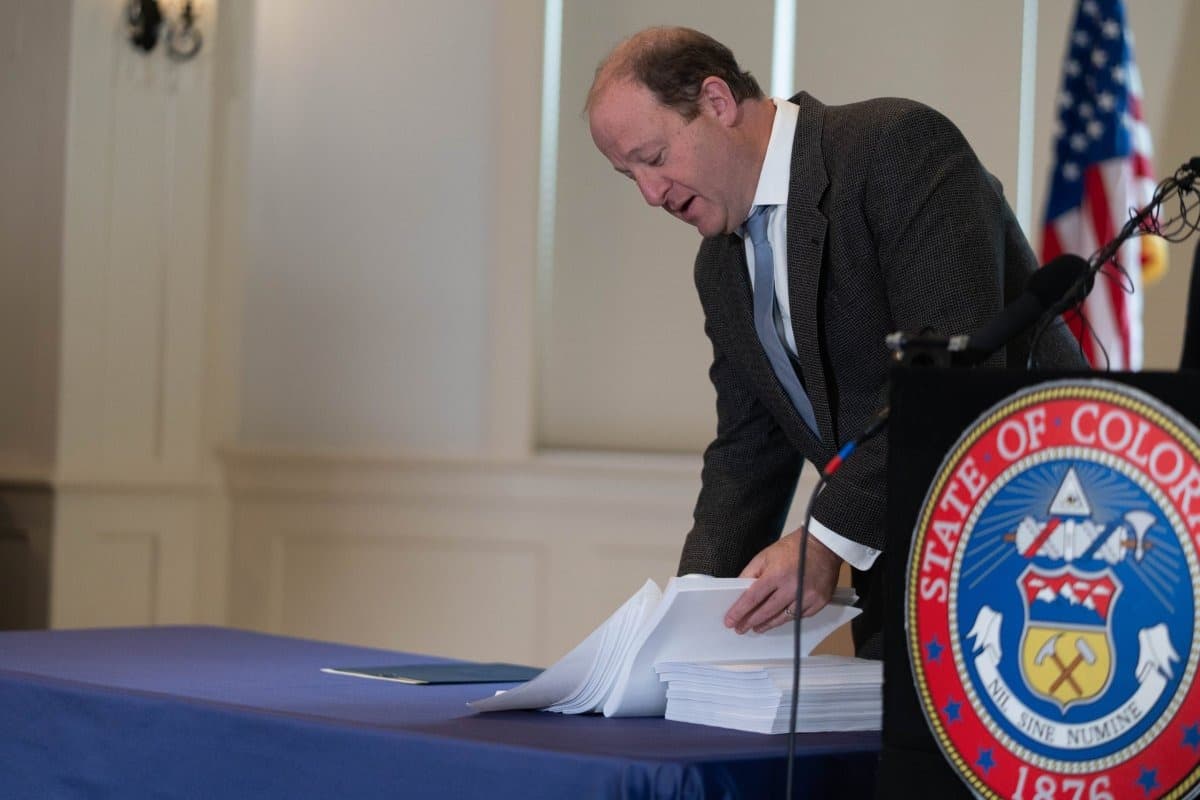 Colorado Gov. Jared Polis sifts through a copy