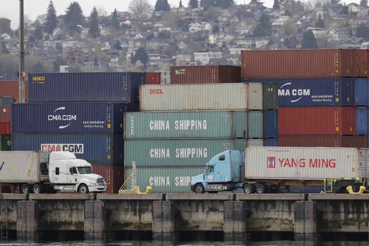 Trucks pass by cargo containers labeled "China Shipping,