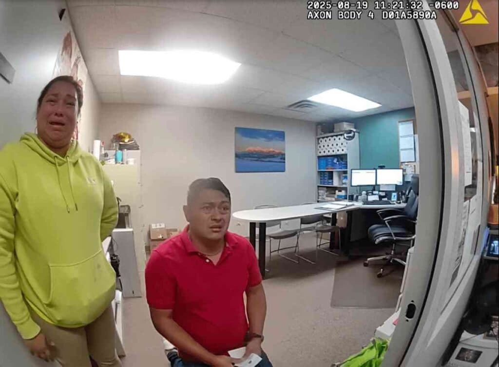 body camera footage of two people looking at the camera, one is standing the other is sitting