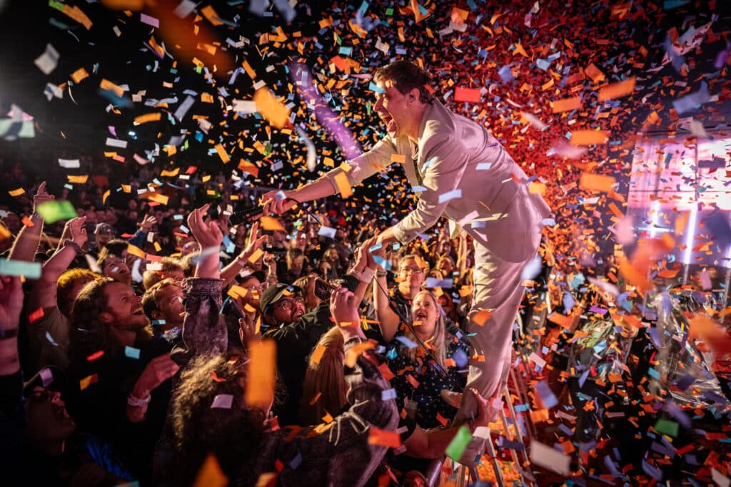 OK Go’s Damian Kulash stands atop the stage barricade and greets fans as confetti rains down at Indieverse