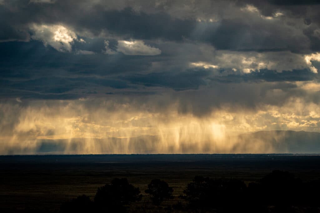 arly evening rain falls across the San Luis Valley, backlit and glowing by the low-angled sun