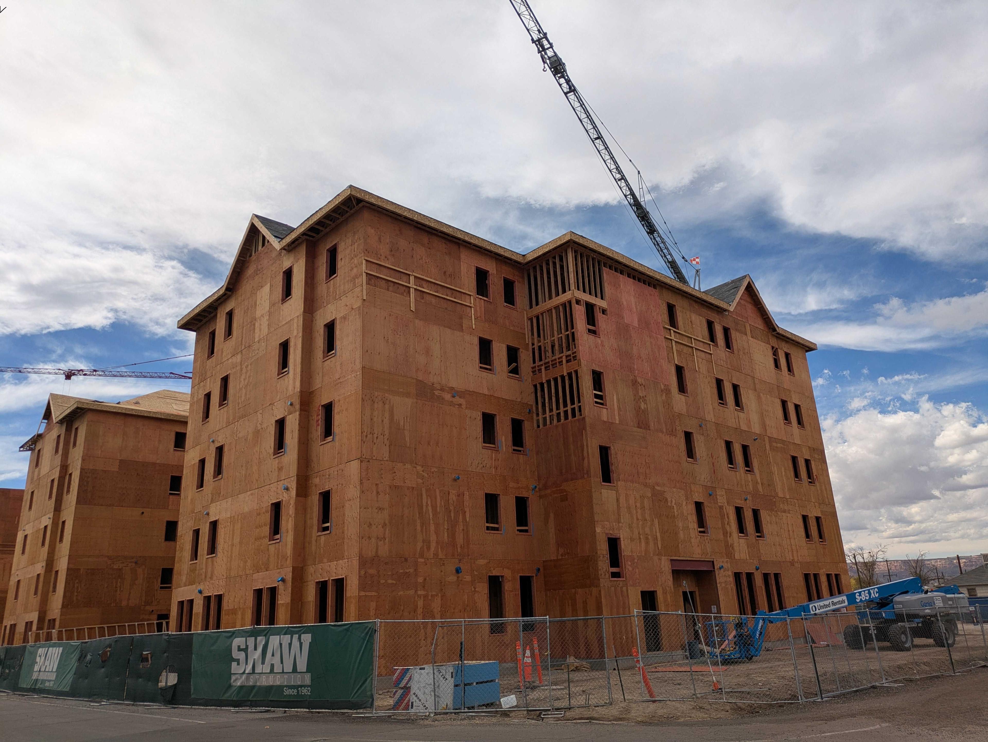 A five story student housing building is seen under construction. A crane can be seen at an angle above the roofline.