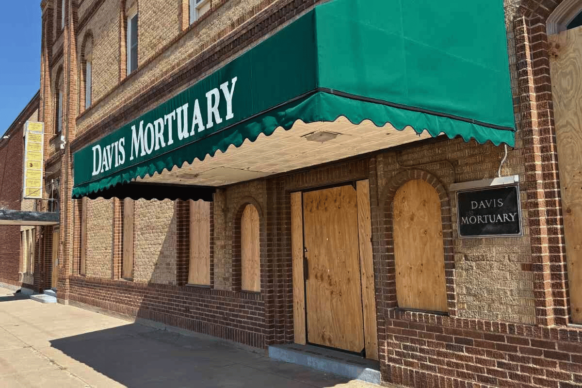 A boarded up building with a green awning
