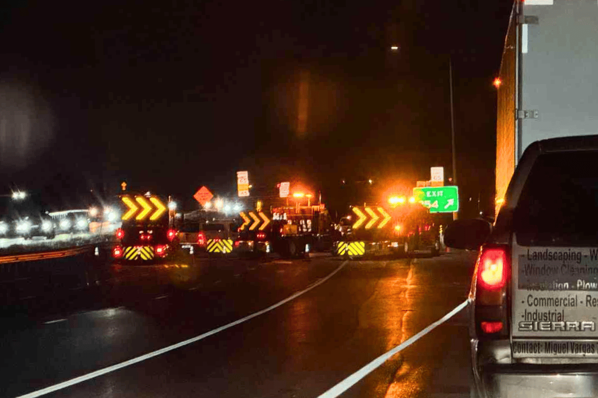A road blocked off at night with emergency vehicles blocking the road