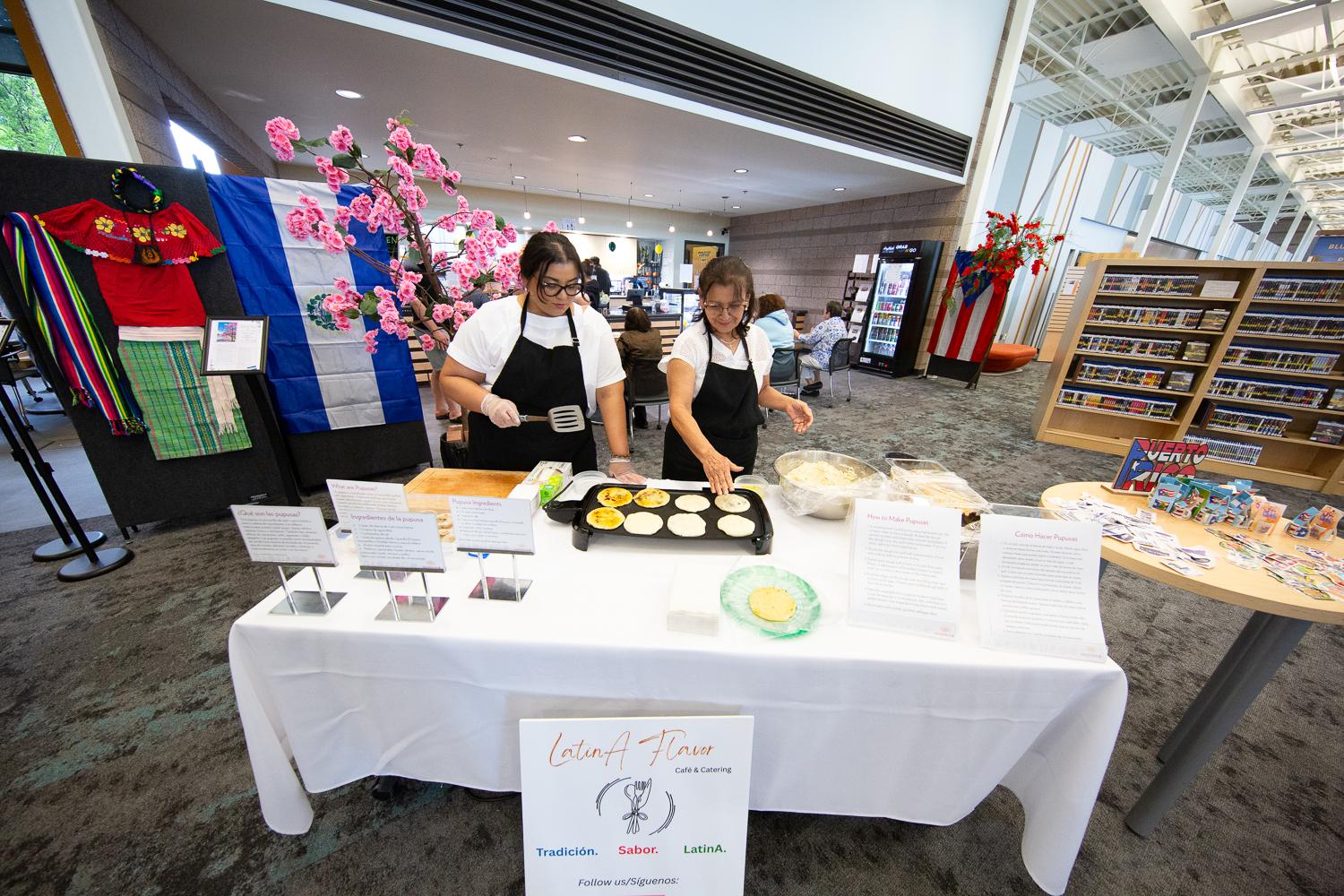 Two women demonstrate how to make papusas.