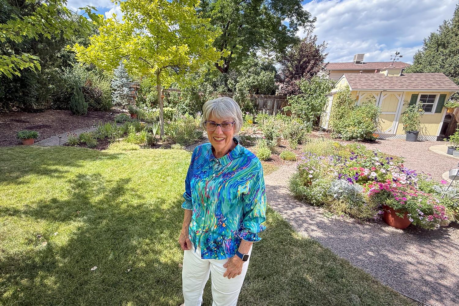 A woman stands in her backyard.