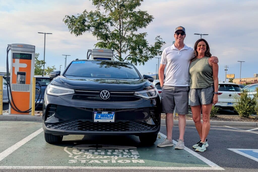 A couple besides a Volkswagen EV in Denver