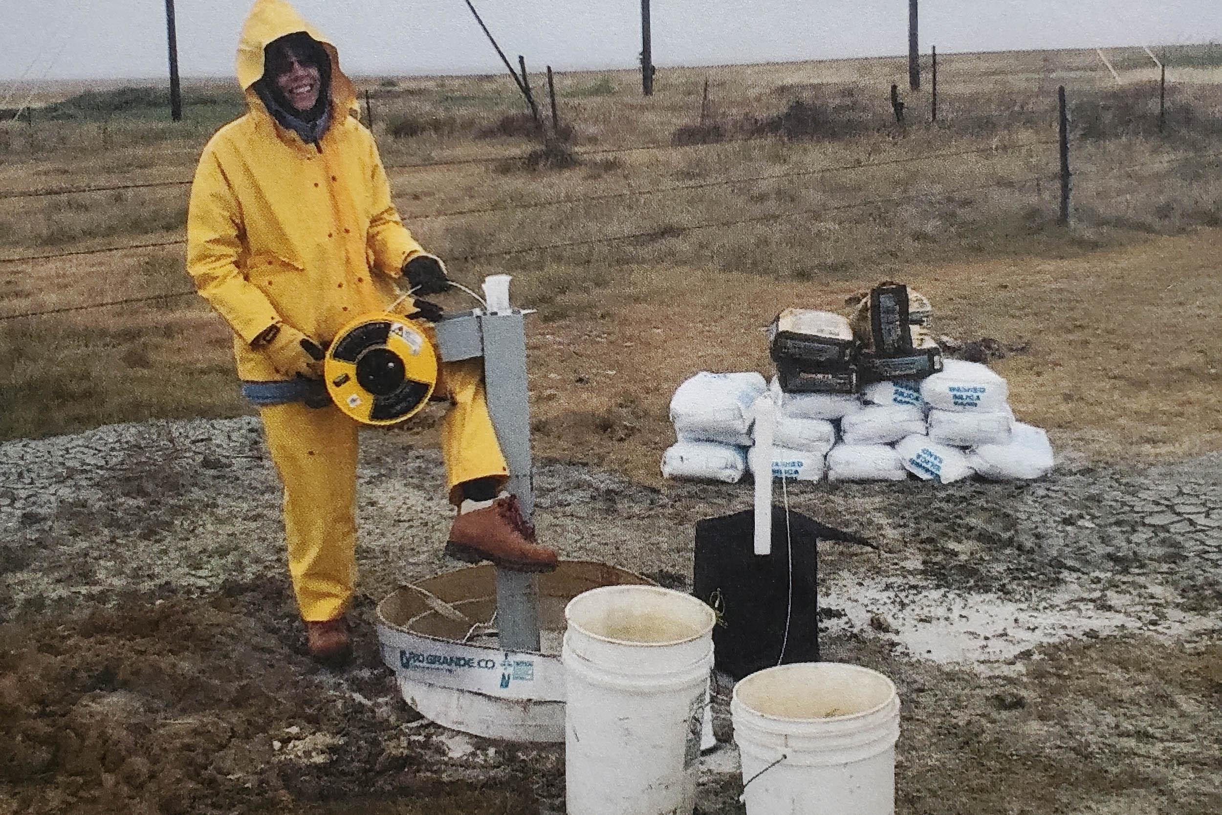 scientist in rain gear works with equipment on a cloudy day
