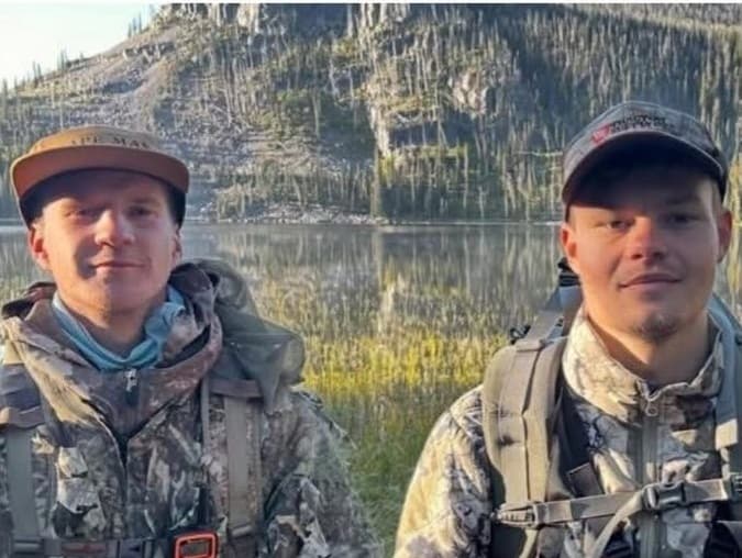 Two men in hunting gear face the camera