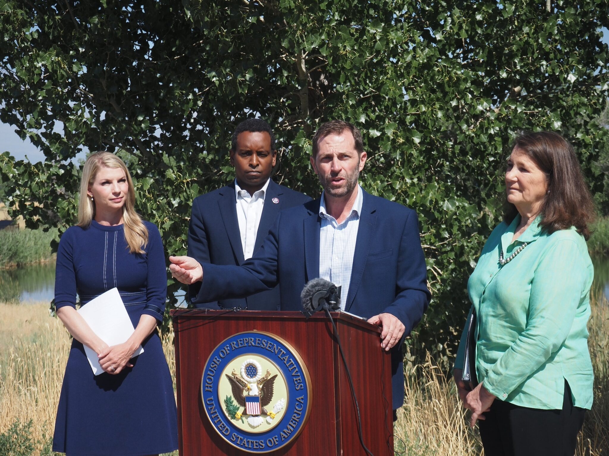 Four people standing in front of a tree at a podium