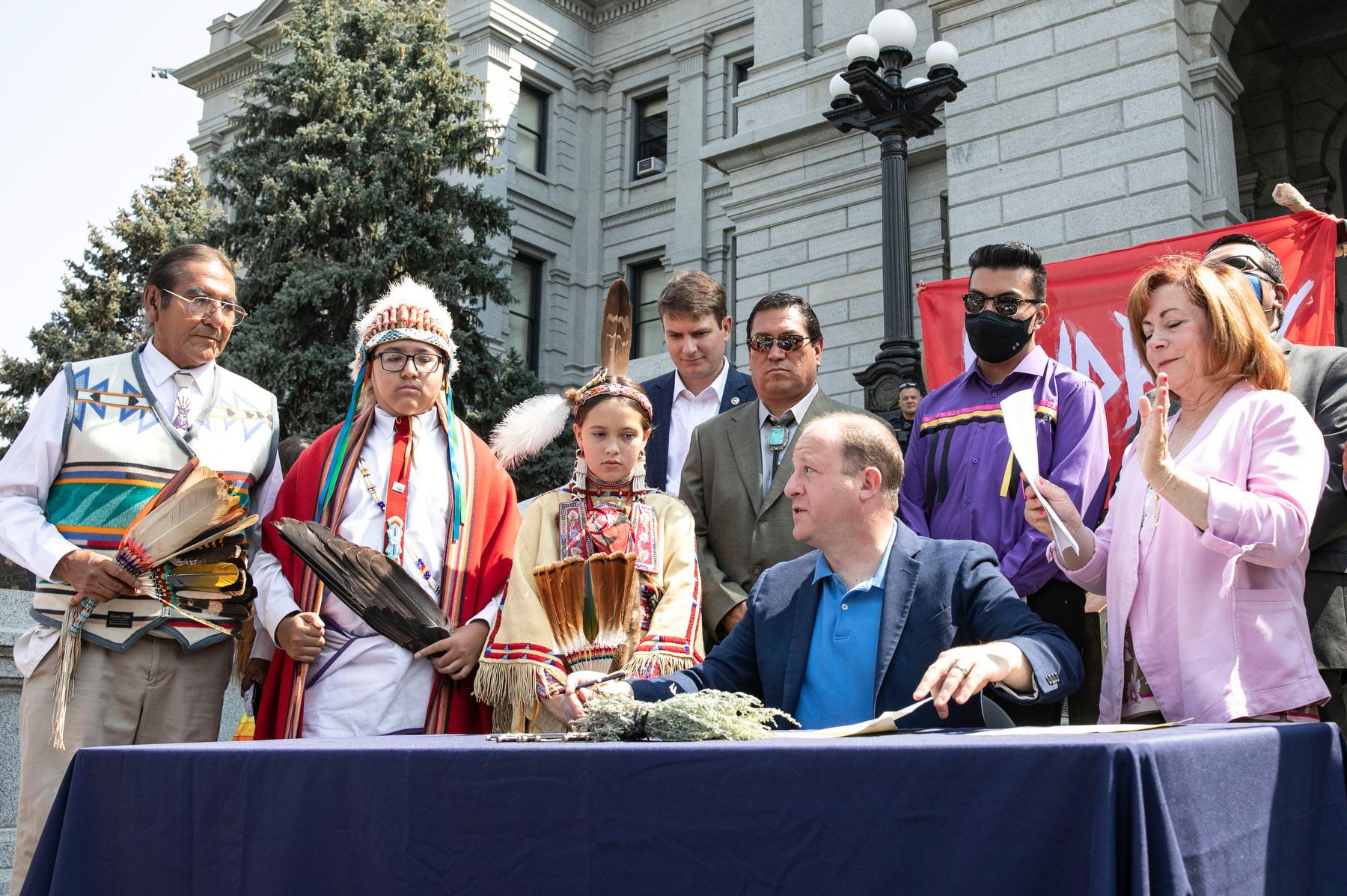 Gov. Jared Polis, surrounded by Colorado and regional tribal leaders