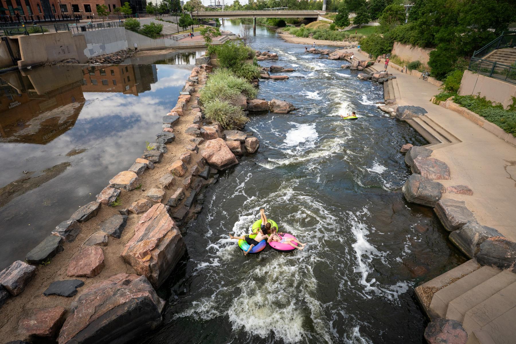 People ride tubes through the rapiuds at Confluence Park