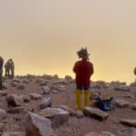 A man stands watching the sunrise from the summit of Pikes Peak