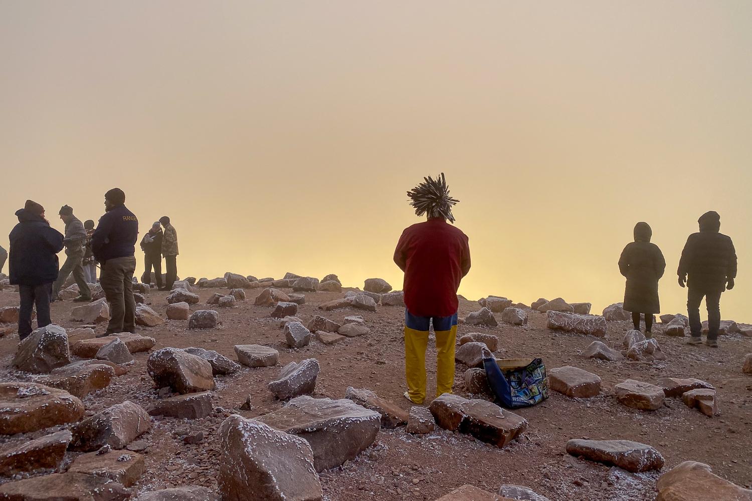 A man stands watching the sunrise from the summit of Pikes Peak