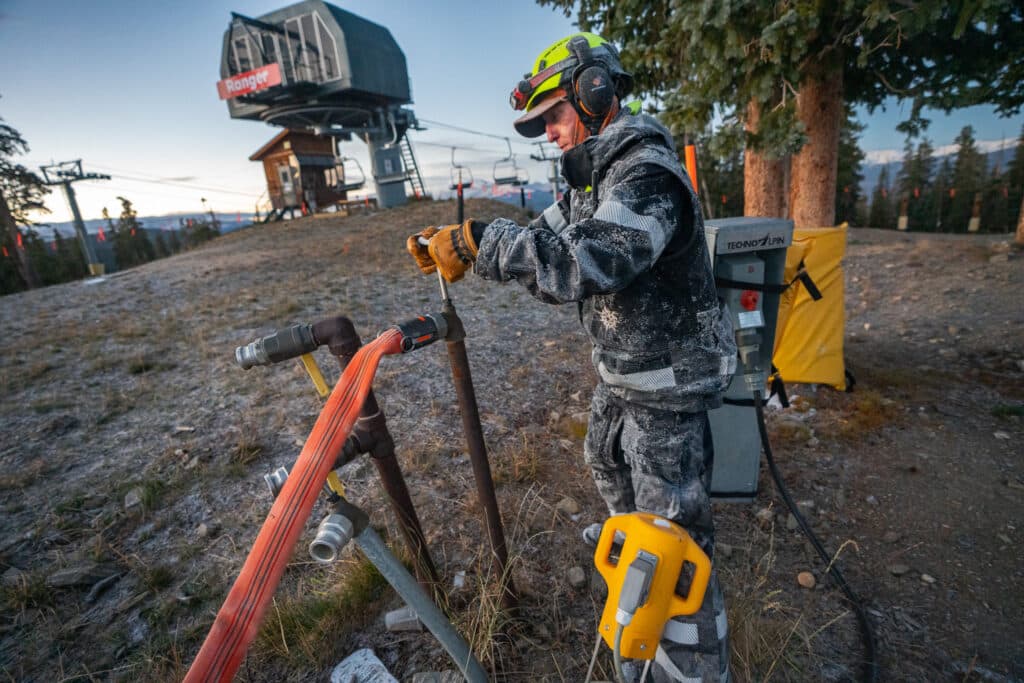 A person stands beside a snowmaking machine