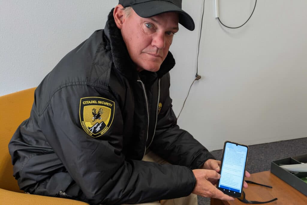 A man in a black jacket holds up his cell phone to show a notice from the State of Colorado that Snap benefits will likely be delayed for the month of November.
