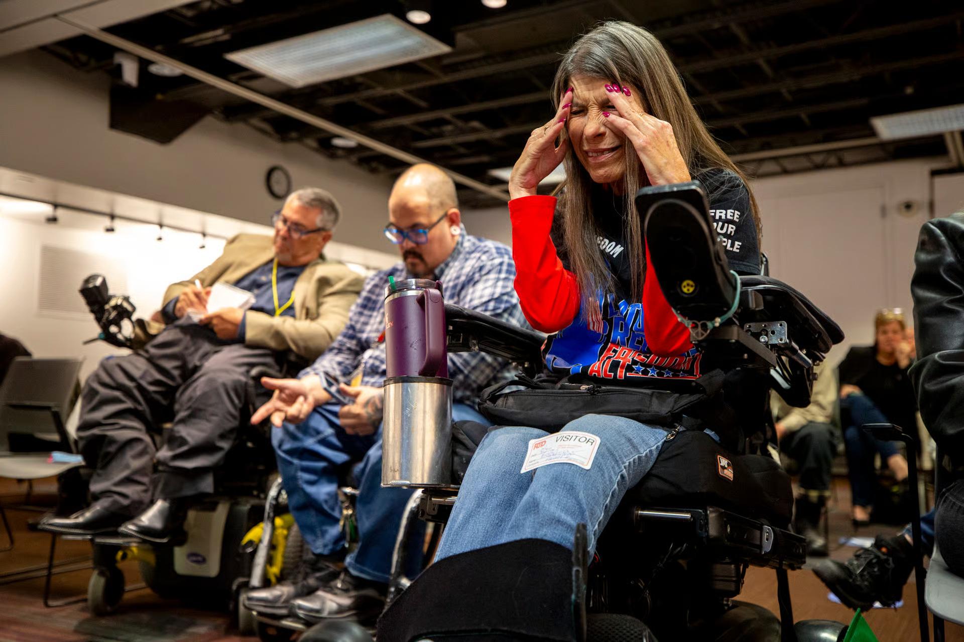 A group of sitting in wheelchairs, engaged in a meeting.
