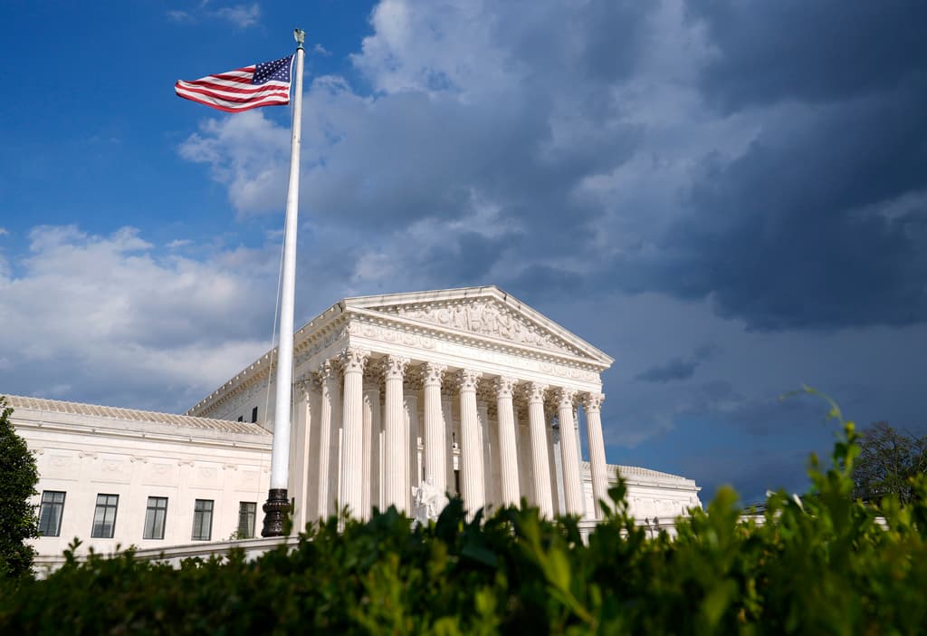The image features a large white building with a prominent American flag flying on a pole.