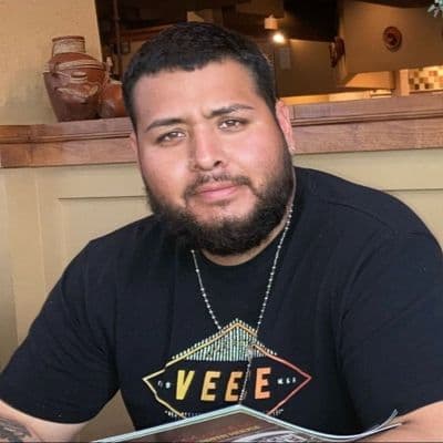 man in black tee shirt with a half smile looking at the camera