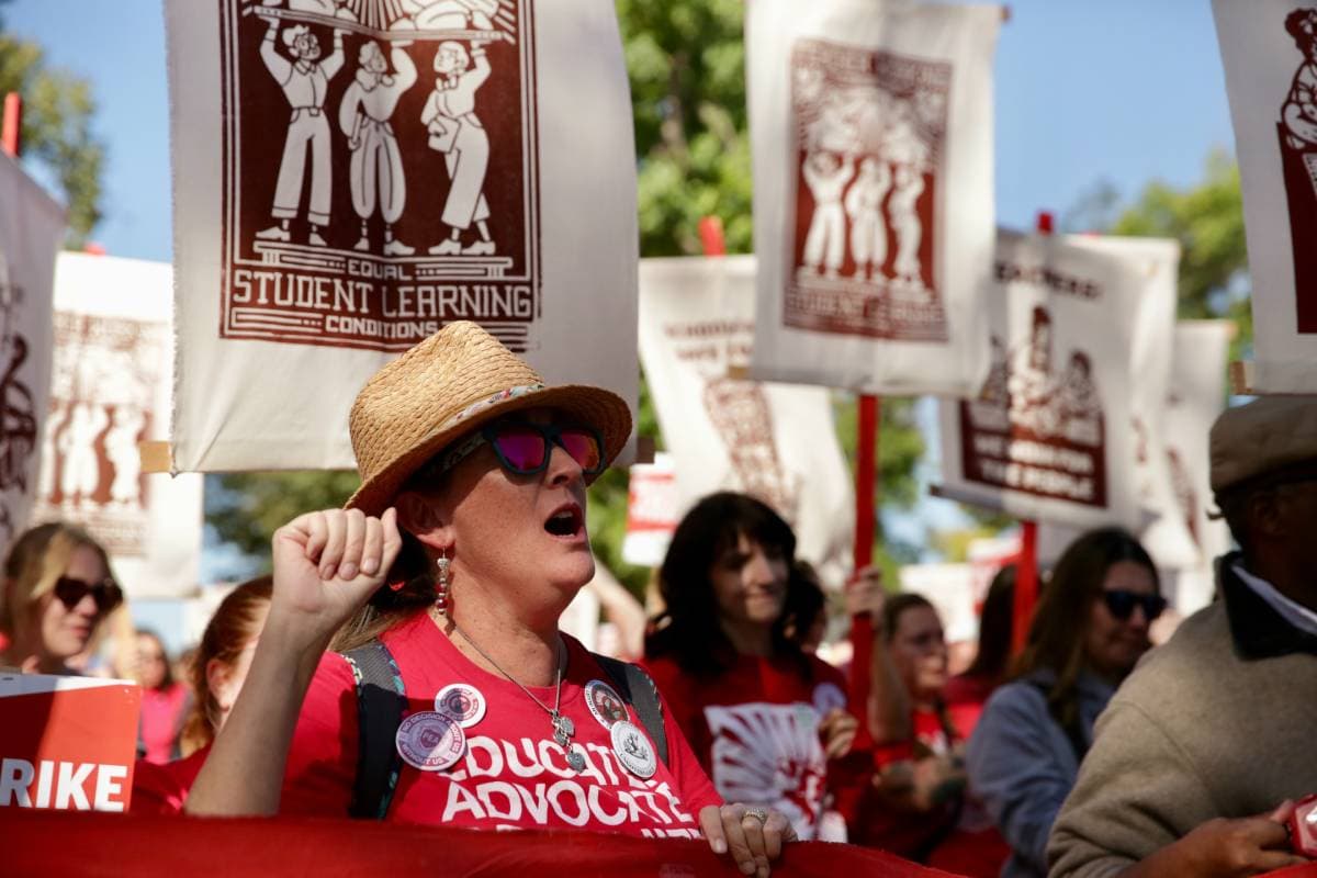 A woman in a straw hat cheers during a rally for teachers.