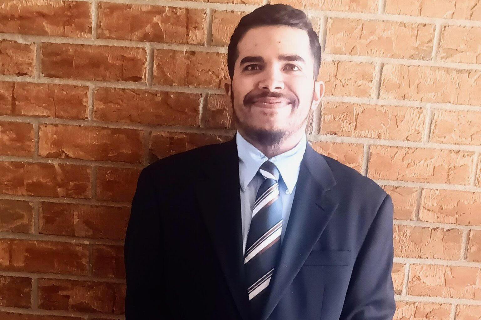 A man wearing a suit and tie is smiling for the camera.