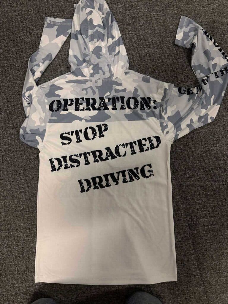 Image shows a white hoodie with a grey pattern on the hood and sleeves and black writing on the front.