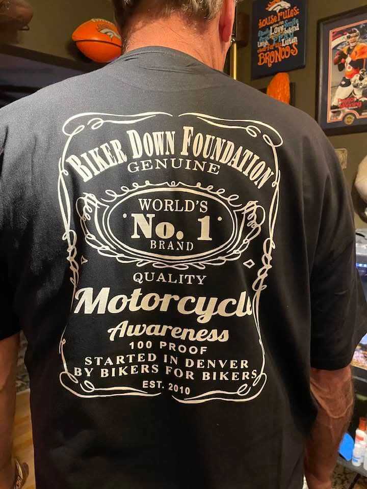 Photo shows the back of a man wearing a black tee-shirt with white writing and logos.
