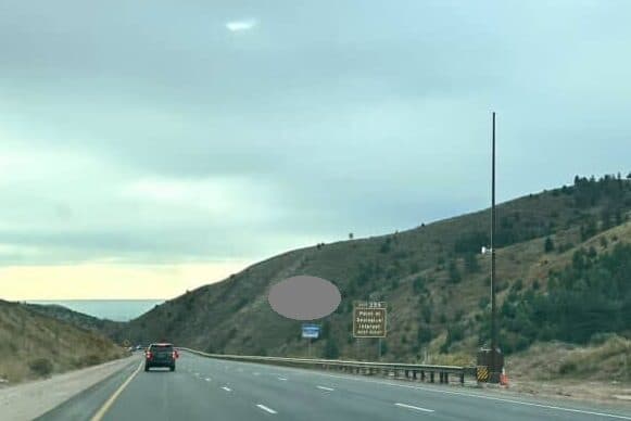 a brown and green hillside southeast of I-70 near Genessee, with a grey oval covering where the swastika appeared.