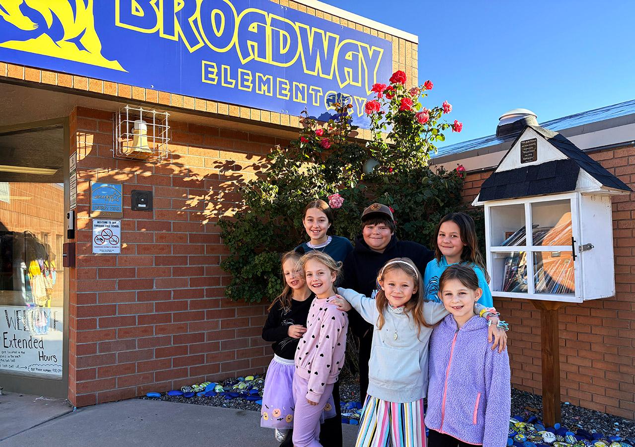 A group of children posing for a picture in front of a school sign.