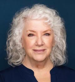 A woman with white hair is smiling for the camera.