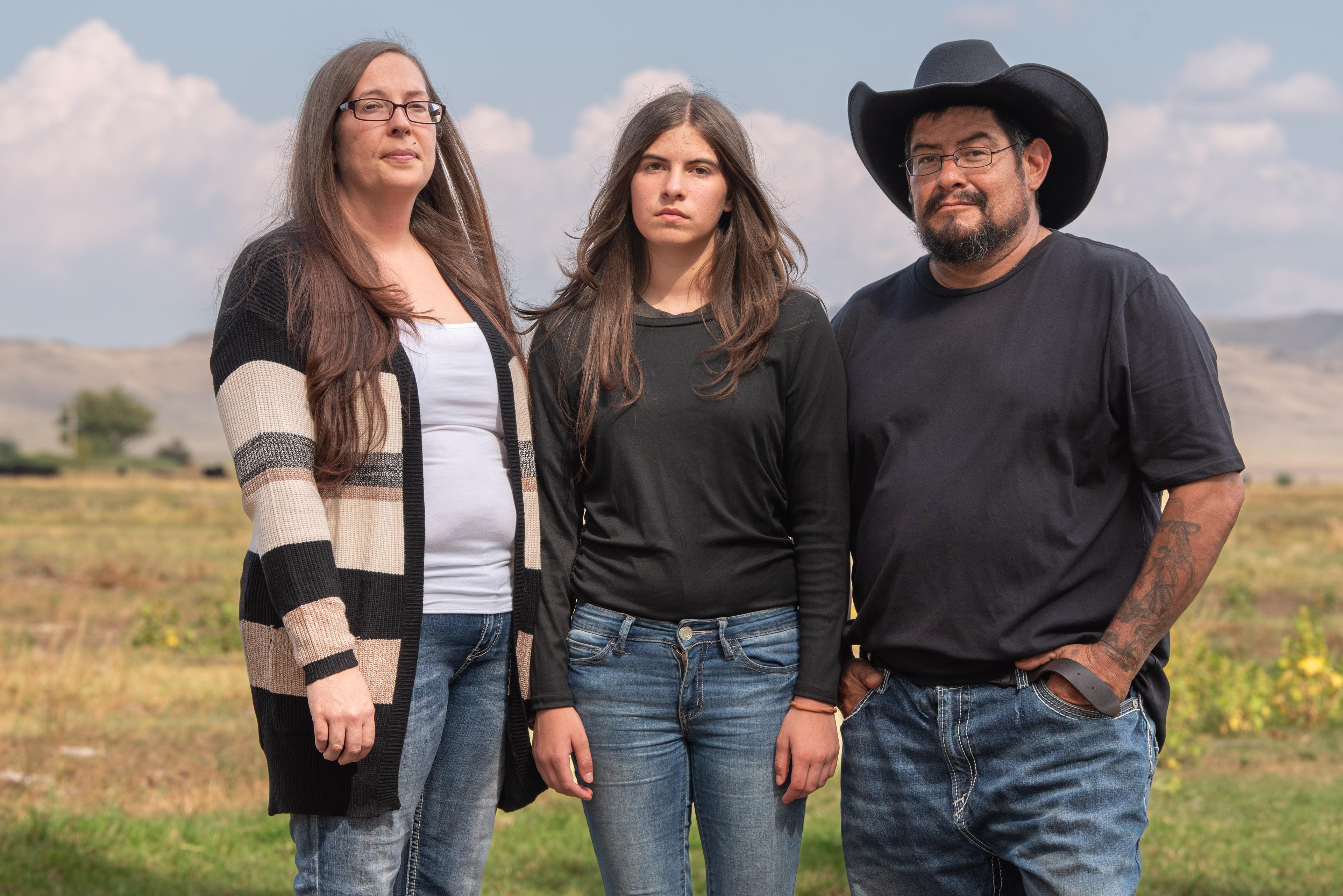 Three people are standing together, posing for a picture.