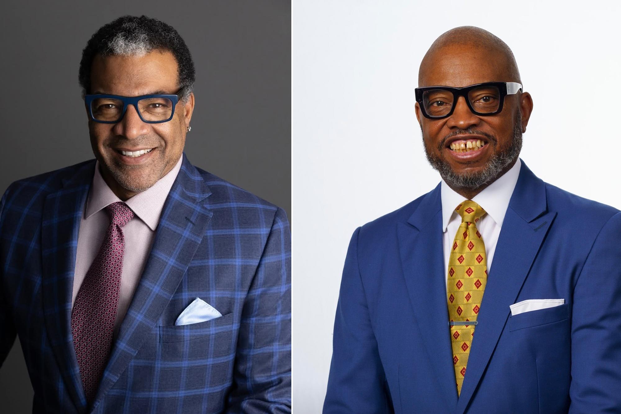 Image shows two men in blue suits wearing glasses