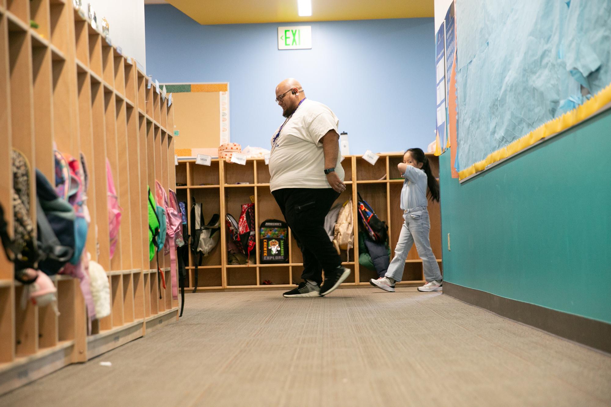 Reading tutor Gabe Martinez leads students to his work desk