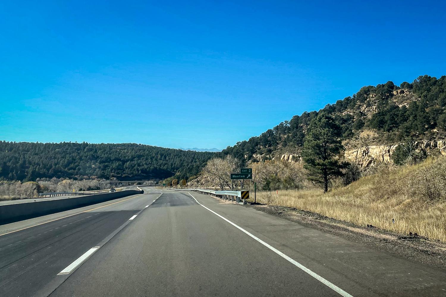 A four lane highway with a hill on the side. The photo is taken from a car driving on the highway that is headed up the hill.