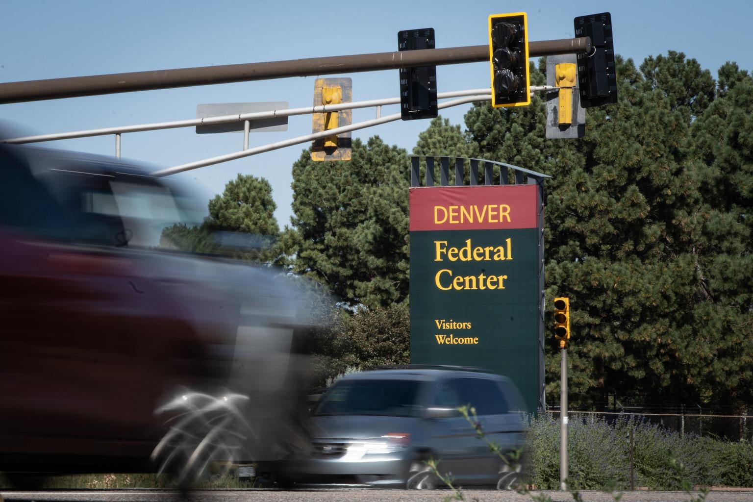 cars drive by a sign for the federal center