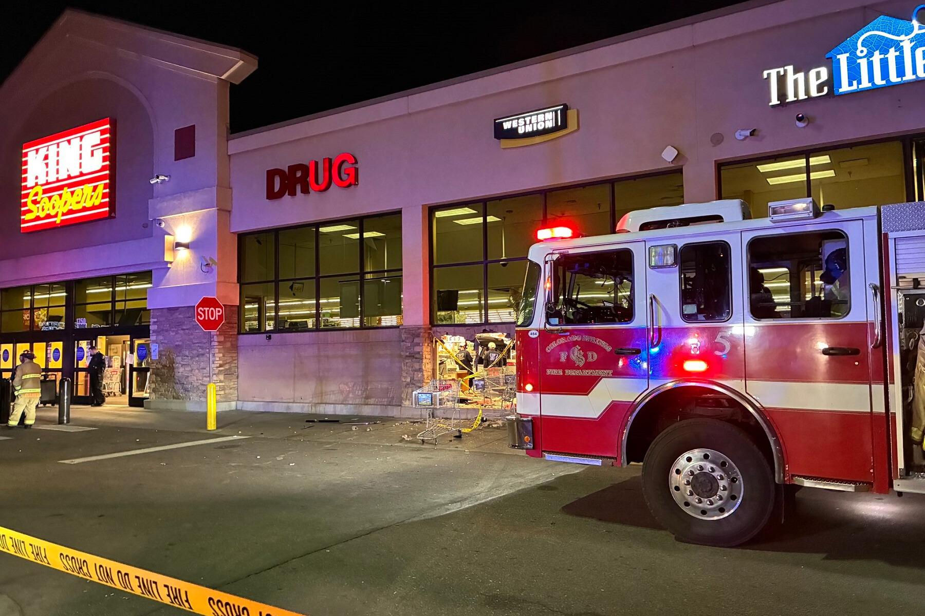 A red fire truck is parked in front of a building that has sustained damage.