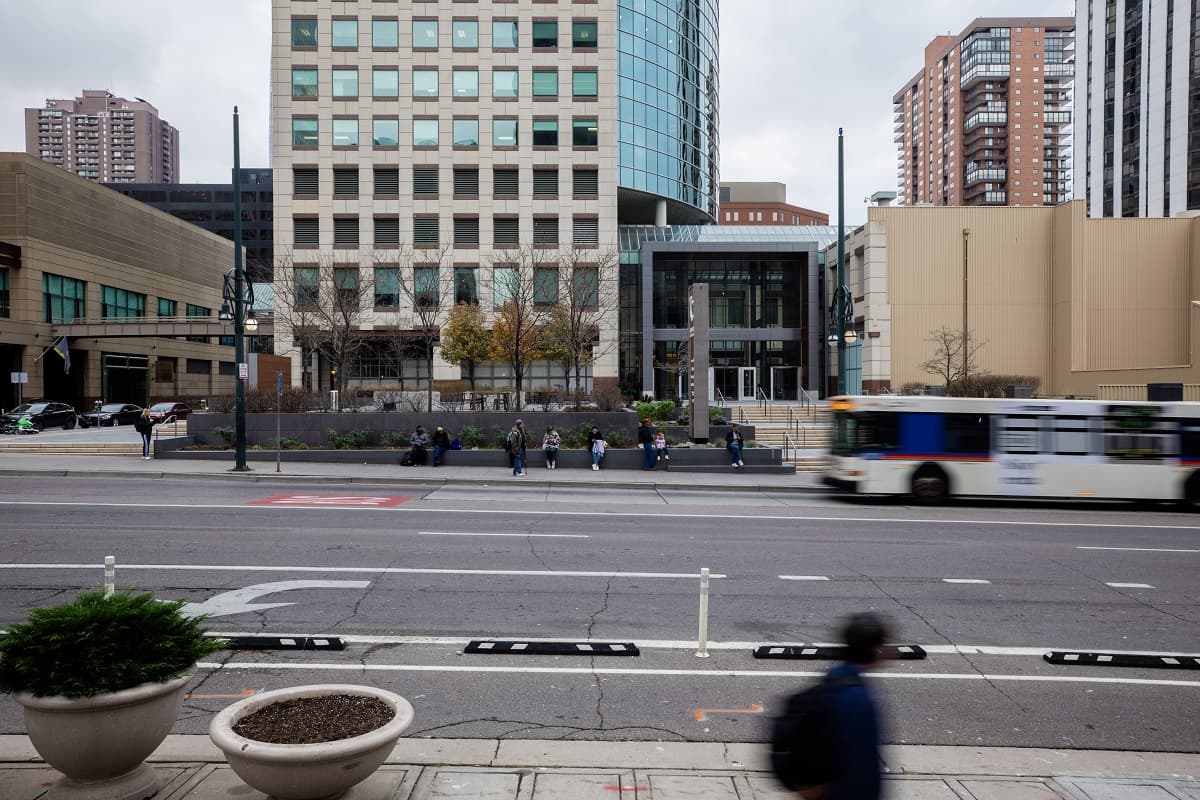 A bus arrives at a stop with people waiting