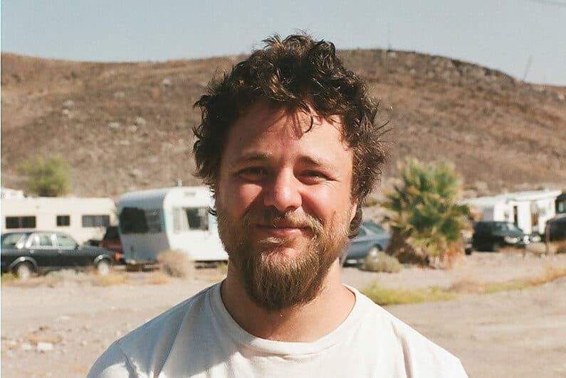 Director Max Walker-Silverman poses in front of trailers in the desert.