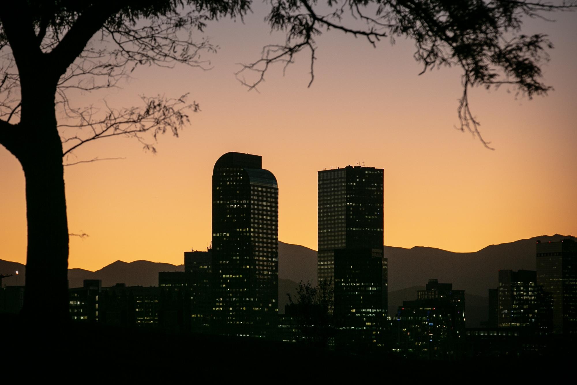 Downtown Denver skyscrapers as the sun sets behind the mountains