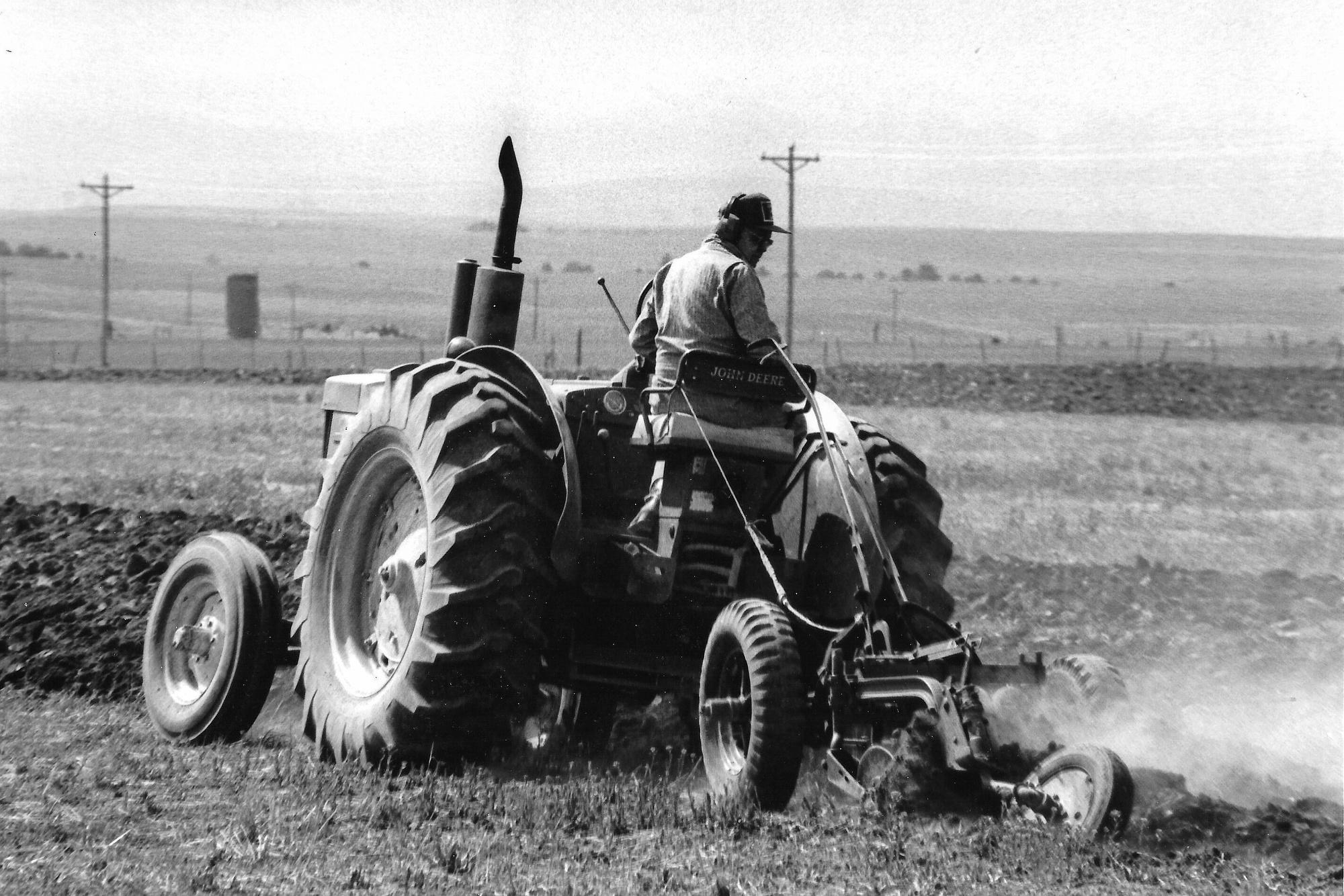 A black and white photo of a man plowing