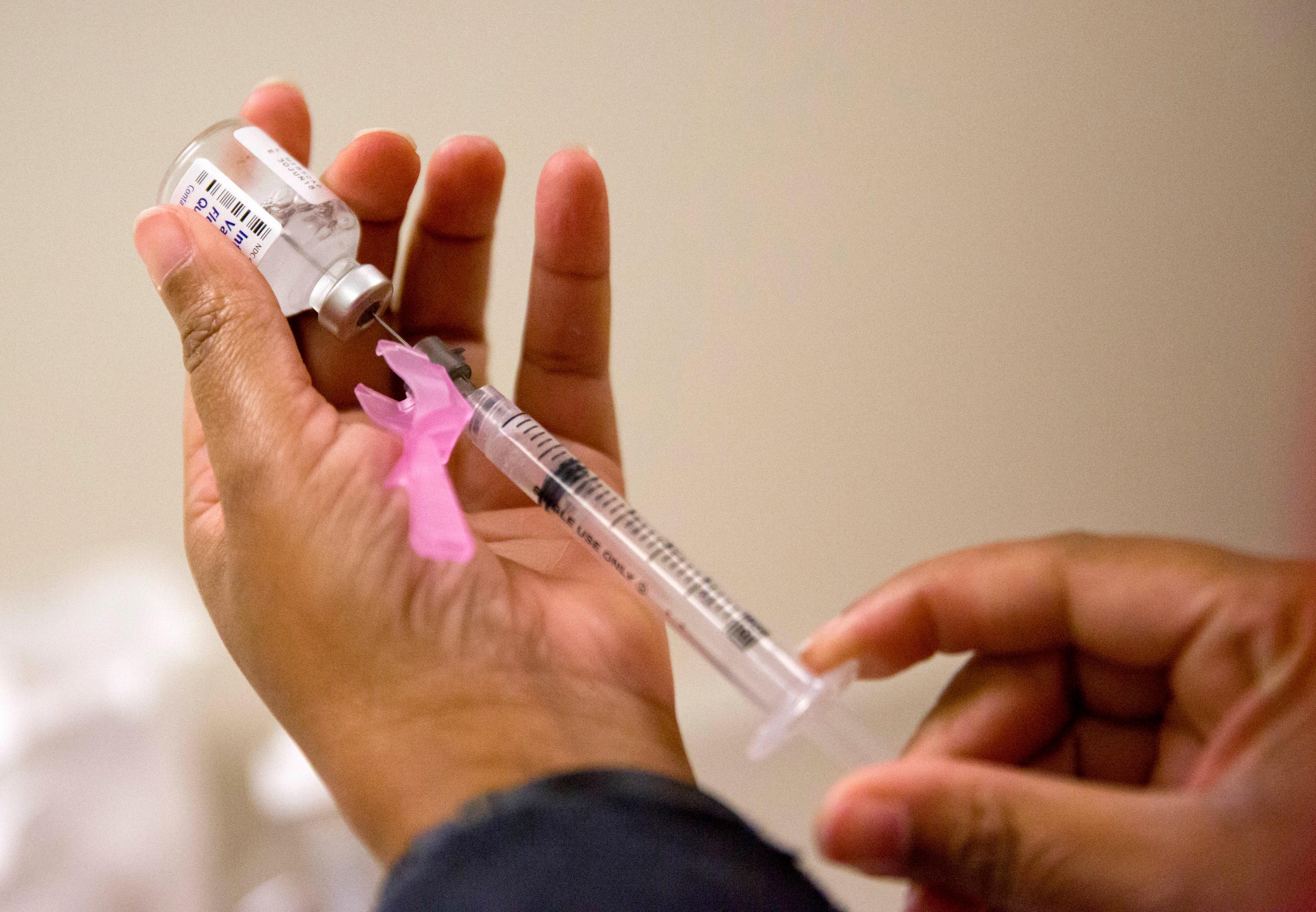A nurse's hands prepare a flu shot