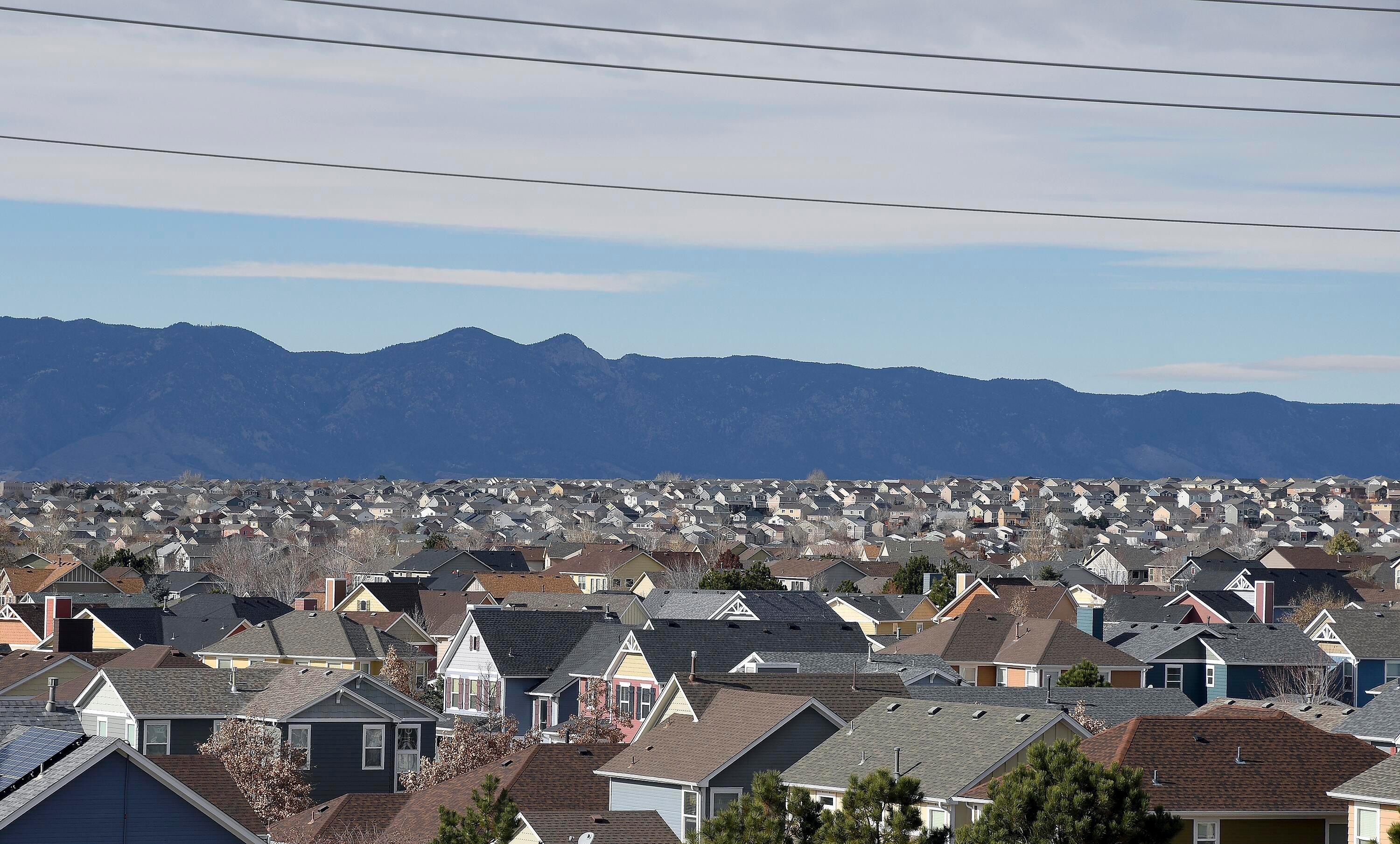 The tops of houses in a sprawling neighborhood with mountains outlined in the background.