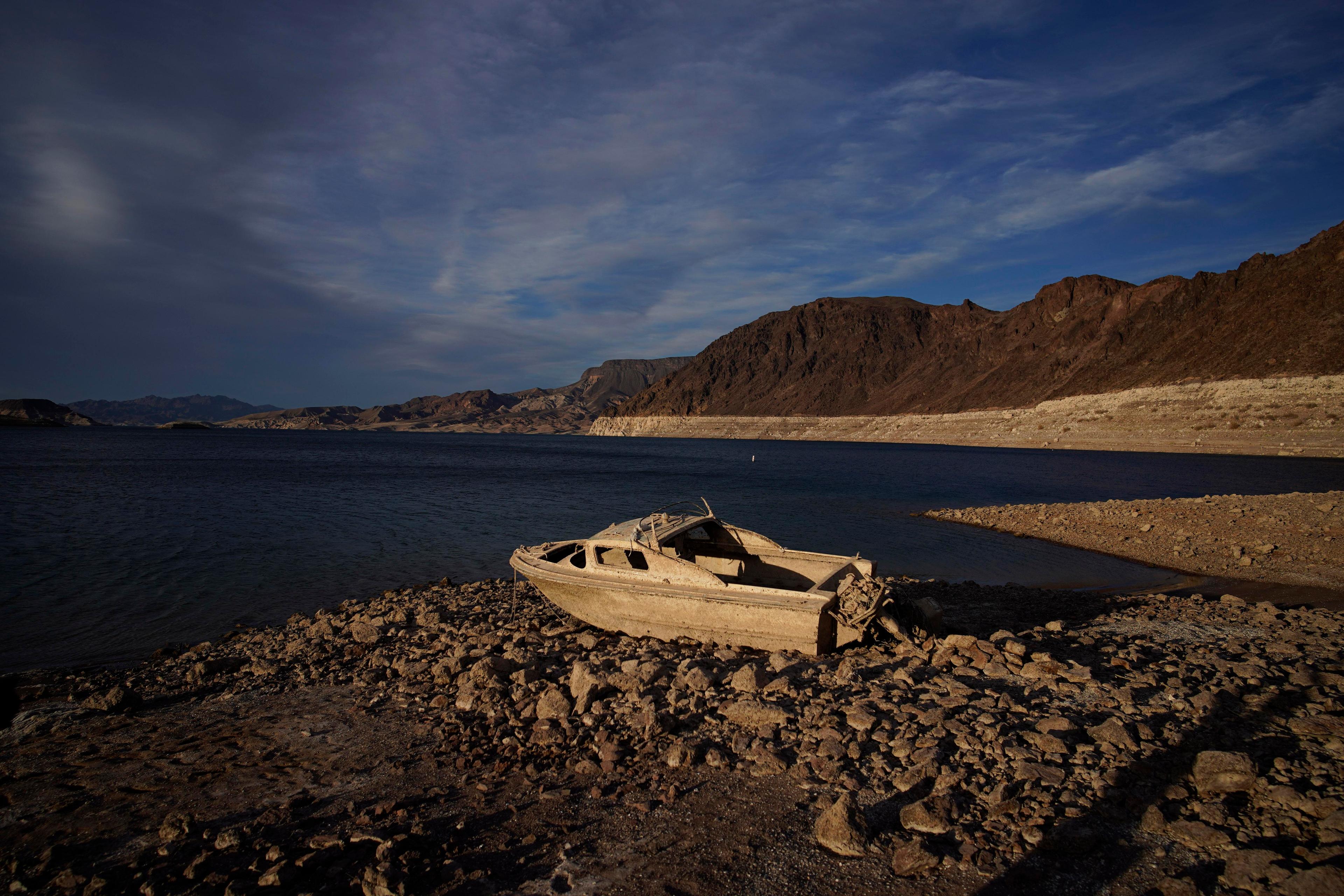 Colorado River An old boat sits on a rocky shoreline that used to be filled with water.