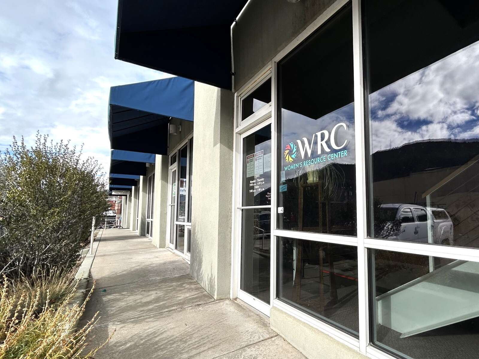 The front of the Durango Women's Resource Center, with blue awnings, and a full glass front displaying a WRC logo.