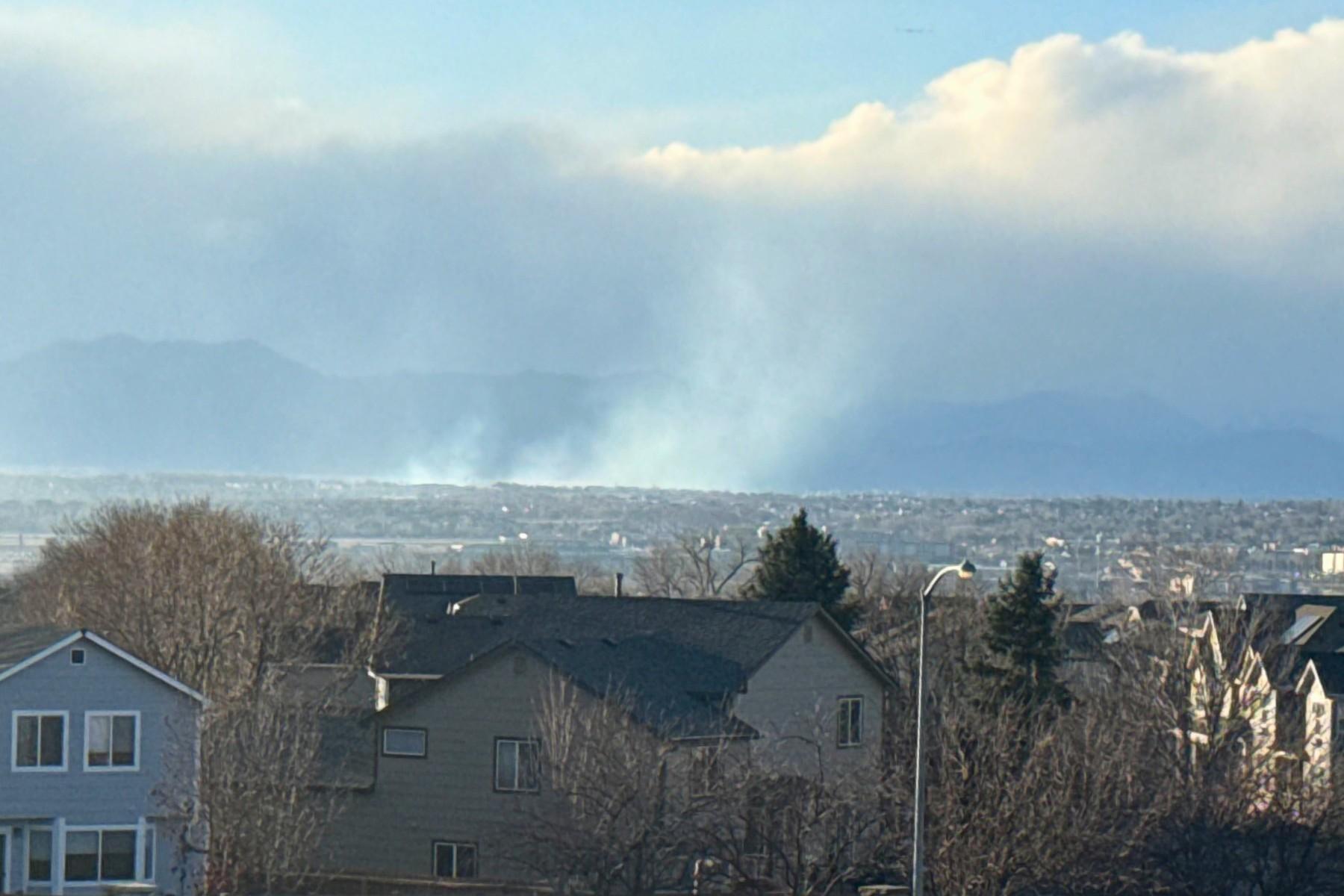 Smoke in the distance, with houses in the foreground and mountain sin the background.