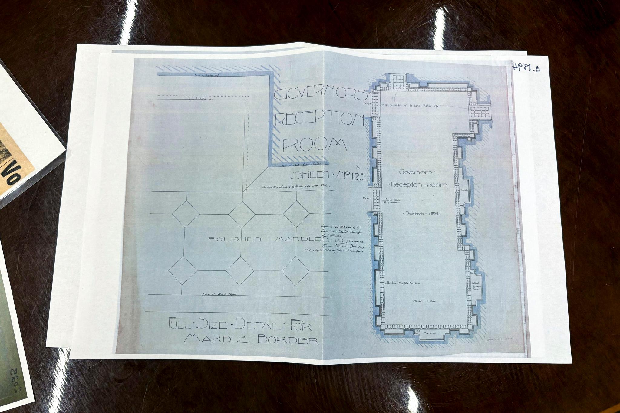 A shot looking down at blueprints that read "governor's reception room."