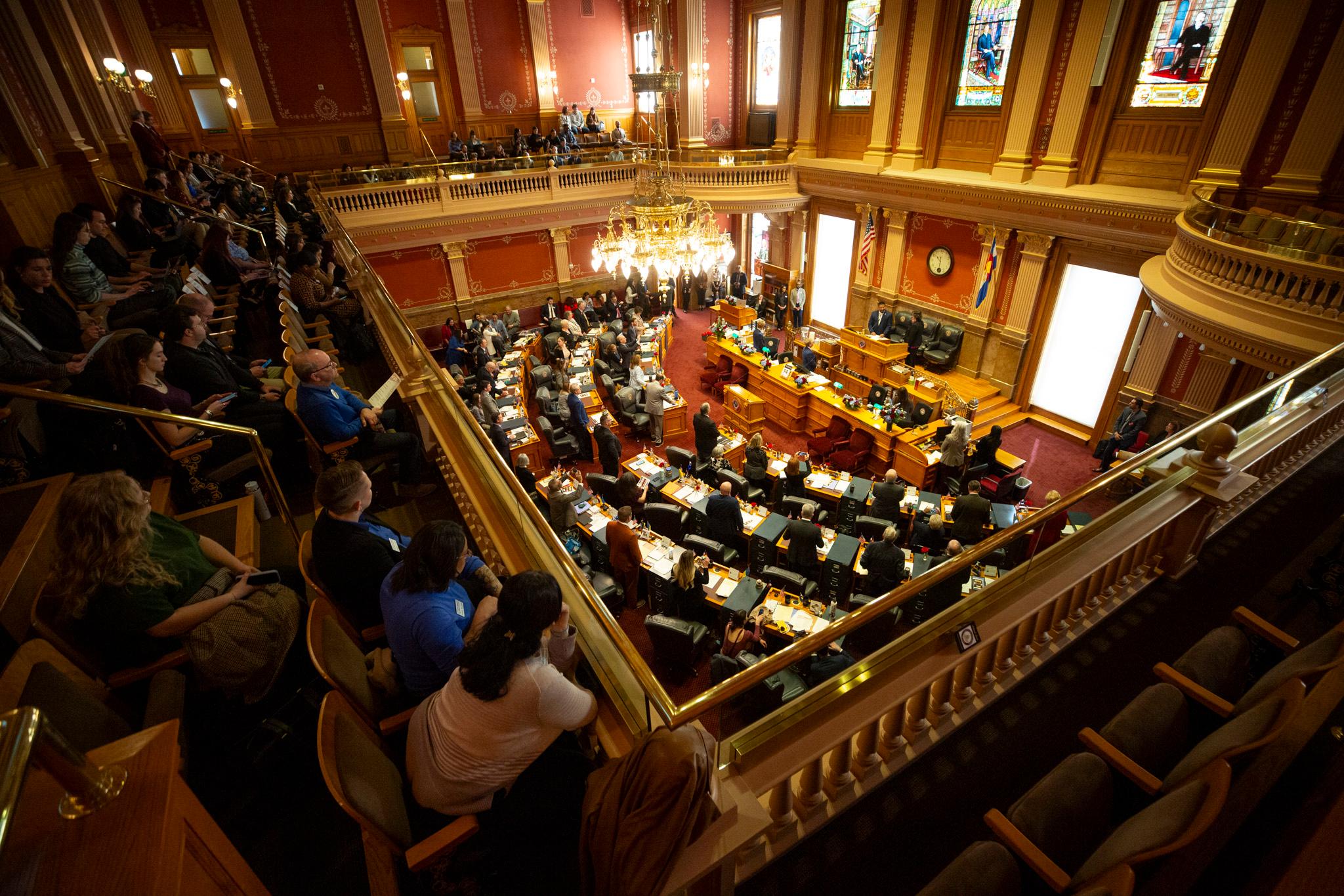 A view down into a red-tinted room full of curved rows of desks and people in suits.