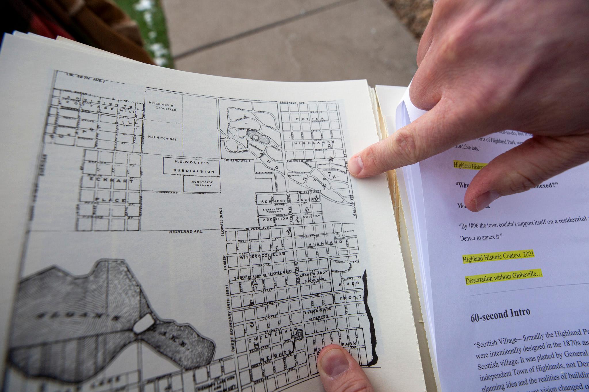 A hand enters the frame from the top right, pointing down at an old map.